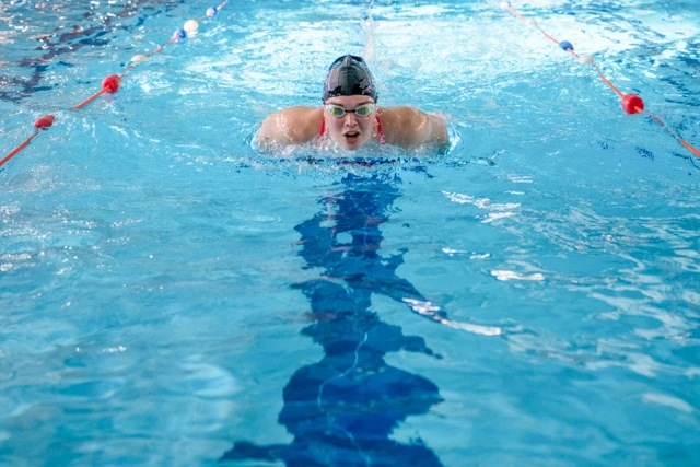 Swimming (7) Swim Fitness class image. Picture of a woman in a swimming pool in a swim hat and goggles.