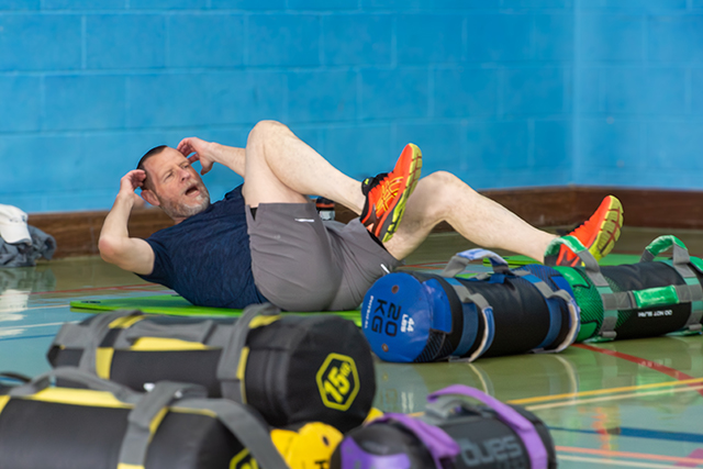 Bootcamp A male class member complets bicycle crunches as part of a bootcamp class