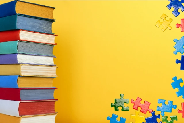 Books, DVDs and Puzzles (1) A stack of colorful books is on the left side of a bright yellow background, while colorful puzzle pieces are scattered on the right.