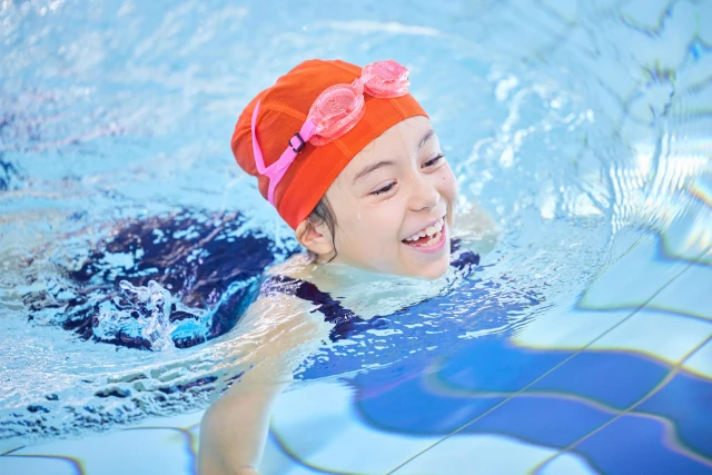 Children's Swimming Lessons A child smiles swimming in a pool